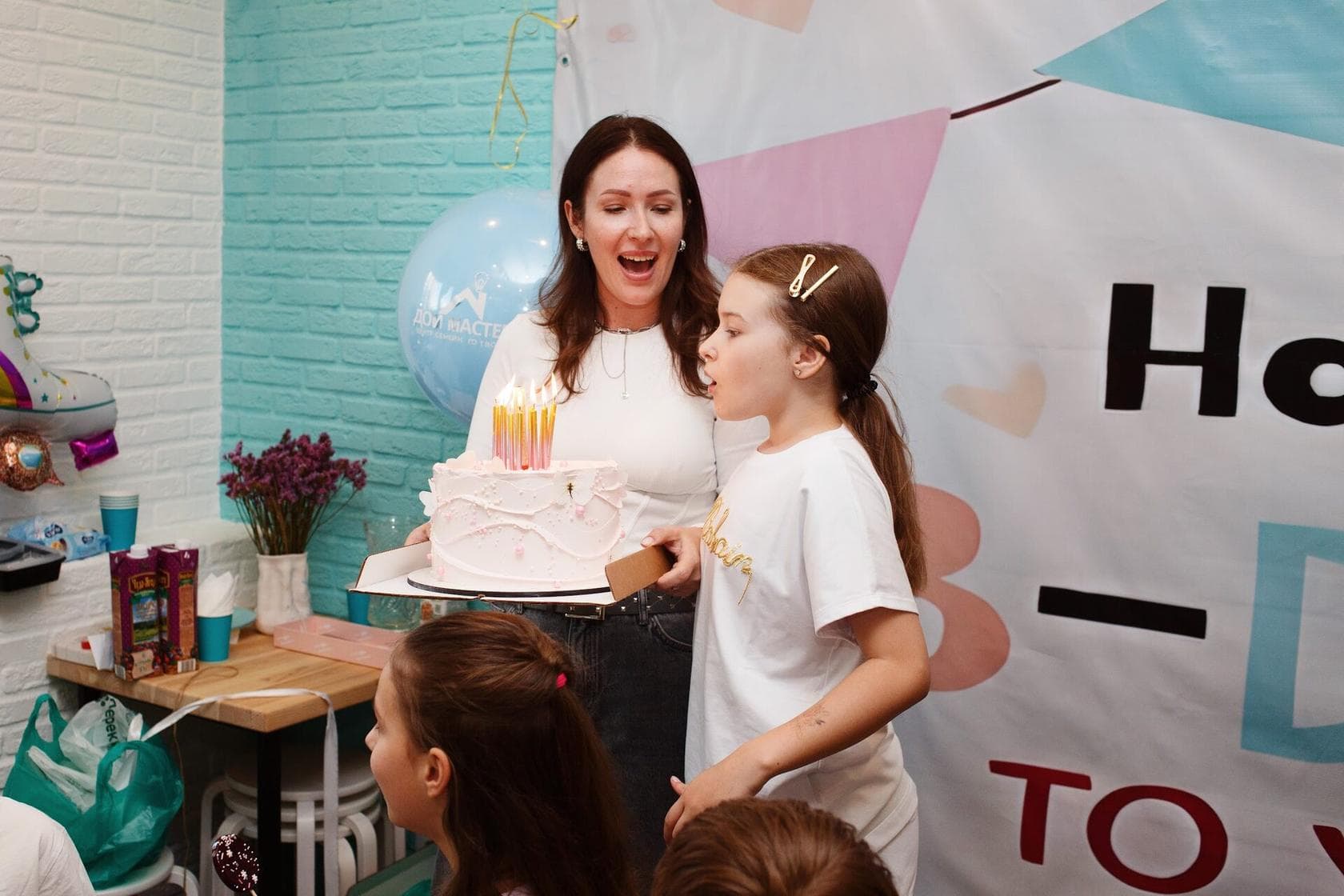 Мама с именинным тортом и дети на празднике в центре