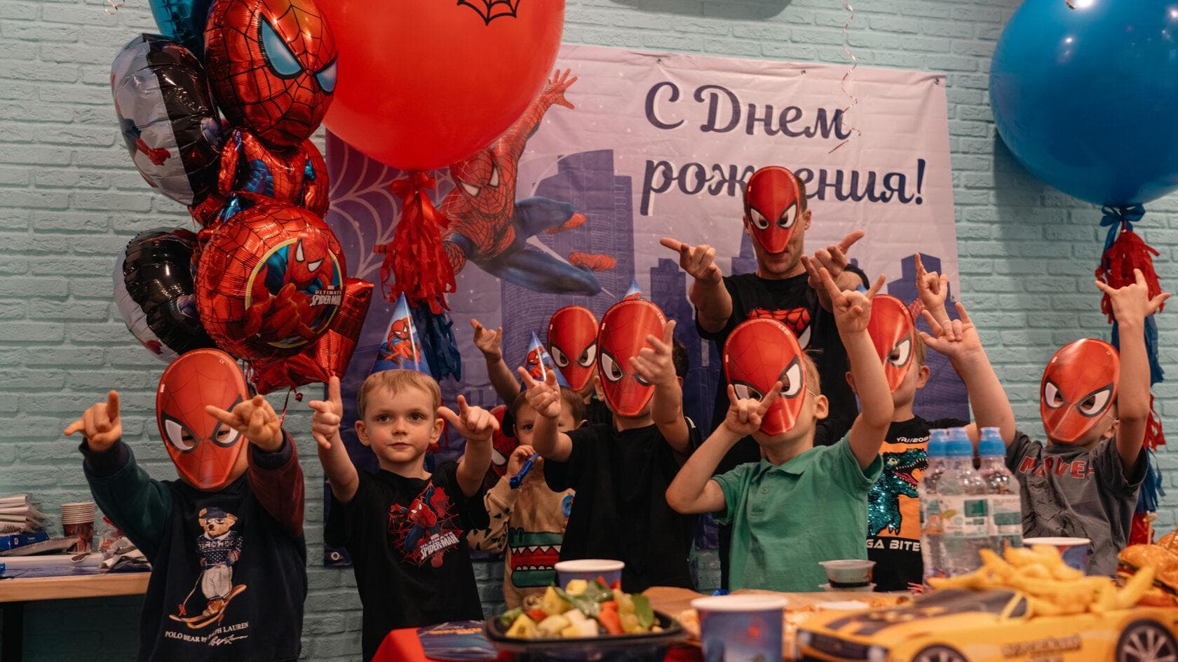 Дети в масках Человека-паука на дне рождения с шарами и плакатом