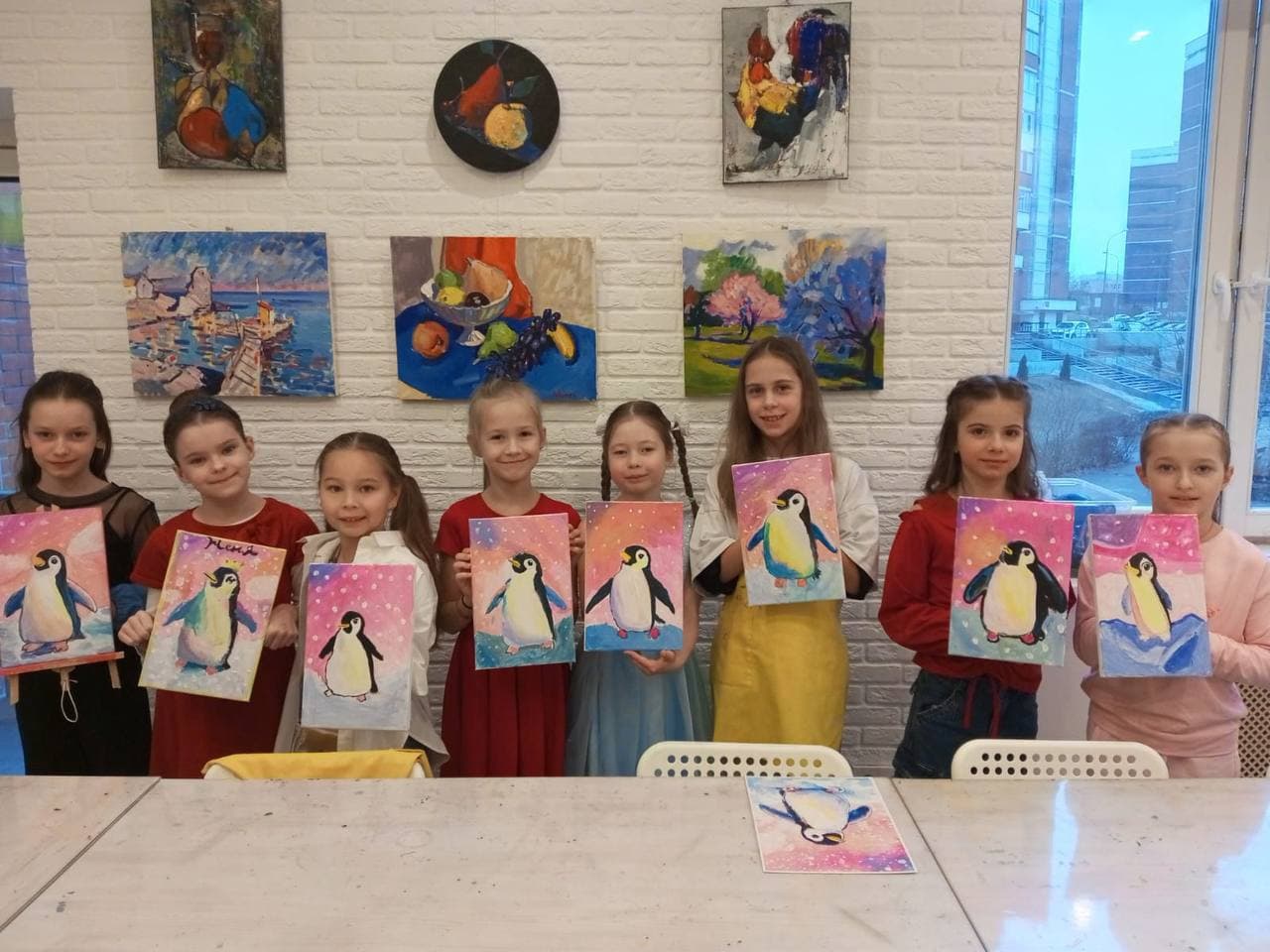Группа детей с готовыми картинами про пингвинов после занятия