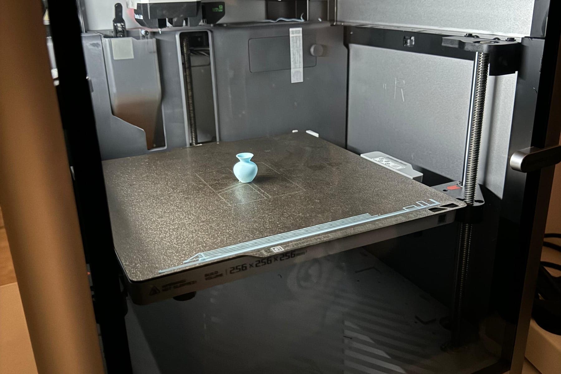 Голубая ваза, напечатанная на 3D-принтере, на его рабочем столе